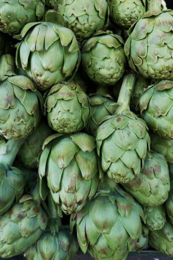 Close-up of fresh green artichokes stacked in abundance at a local market.